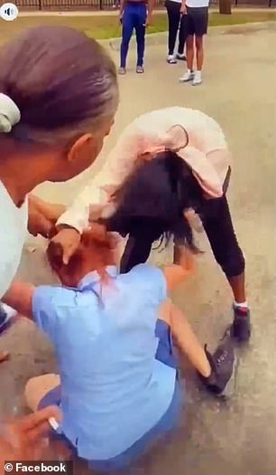 An elderly woman is seen trying to intervene as the women batter the USPS worker on the ground